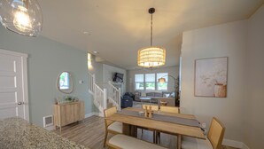 Ein geräumiger Essbereich mit einem Holztisch und Bänken, eine Treppe, die zu einer oberen Ebene führt, und ein großes Fenster, das für natürliches Licht sorgt.