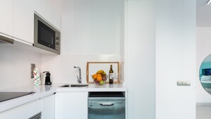 A modern kitchen with white cabinetry, a built-in microwave, a dishwasher, and a fruit bowl with a bottle of wine. - Apartment in Las Palmas Near Las Canteras Beach (Las Palmas de Gran Canaria)