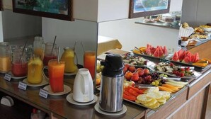 Un bufé de desayuno con diversas frutas, jugos y una cafetera.