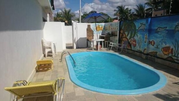 Una piscina con un mural en la pared contigua, una pequeña mesa y algunas sillas.