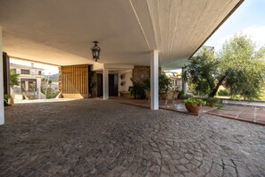 Un patio espacioso con suelo de piedra, plantas en macetas y una puerta de madera con listones.