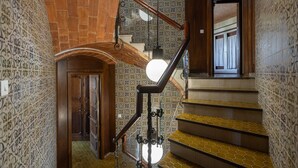 Eine Treppe mit gemusterten Wänden, einem Holnlauf und einer runden Leuchte.