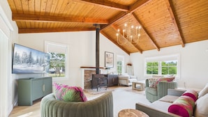 A spacious living area with a high wooden ceiling, a fireplace, a television, and comfortable seating. - Eureka Hotel (New Shoreham)