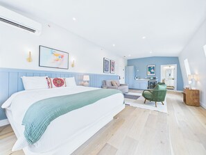 Un dormitorio moderno con una cama grande, una zona de estar y un baño visible a través de una puerta abierta.