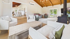 A spacious living area with wooden beams, a fireplace, and a view to the outdoors. - Eureka Hotel (New Shoreham)