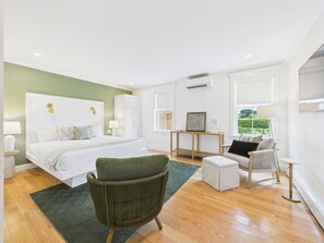 Un dormitorio moderno con una cama grande, un sillón verde, una mesita y un sofá.