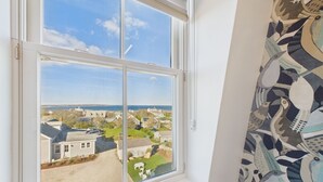 A window with a view of a residential area, a clear sky, and a patterned curtain. - Eureka Hotel (New Shoreham)
