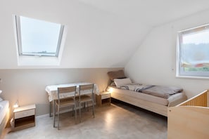 A small, well-lit room with a bed, a desk with a chair, and a window. - Apartment 'Am Bach' with Private Terrace, Balcony and Wi-Fi (Unterkirnach)