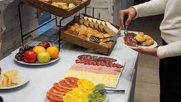 A buffet with various food items including fruits, cheeses, meats, and pastries.