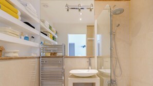 Une salle de bain moderne avec une douche à parois de verre, un lavabo encastré et un porte-serviettes où sont soigneusement pliées les serviettes.