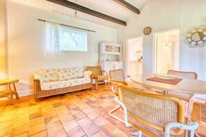A cozy room with a sofa, wicker chairs, a dining table, and a cabinet. - Gîte La Cascade - Domaine l'Étang des Mirandes with Shared Pool (Varaignes)