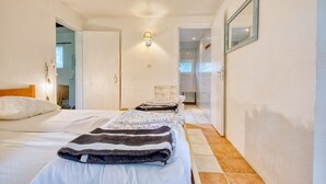 A narrow hallway leading to a bedroom with a bed, a chair, and a wall-mounted lamp. - Gîte La Cascade - Domaine l'Étang des Mirandes with Shared Pool (Varaignes)