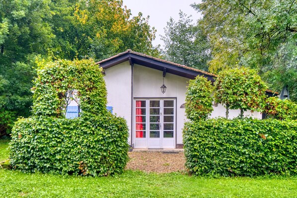 A small building with a white exterior, a red door, and a small porch area.