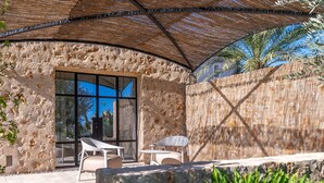 A stone exterior wall, a glass door, and outdoor seating under a shaded area. - Country House 'Agata' with Private Pool, Wi-Fi and Air Conditioning (Illes Balears)