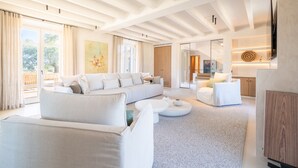 A spacious living room with a large sofa, a coffee table, and a TV mounted on the wall. - Country House 'Agata' with Private Pool, Wi-Fi and Air Conditioning (Illes Balears)