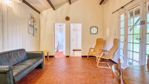 Une pièce comprenant un canapé en cuir, deux fauteuils en osier, une table en bois et une grande fenêtre donnant sur un beau paysage.