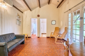 Une pièce comprenant un canapé en cuir, deux fauteuils en osier, une table en bois et une grande fenêtre donnant sur un beau paysage.