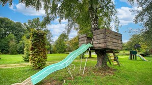 A playground with a slide and a treehouse structure.