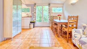 A kitchen with a dining area, wooden furniture, a cabinet, and a window with curtains.
