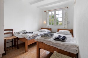 A small, clean room with two wooden beds, a wooden chair, and a window with curtains. - Gîte Le Lavoir - Domaine l'Étang des Mirandes with Shared Pool (Varaignes)