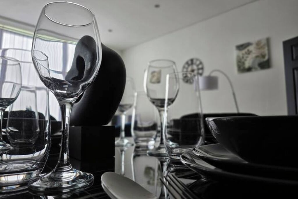 A dining table with multiple wine glasses and plates, reflecting light from the window.