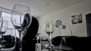 A dining area with a table set for a meal, glasses, and a clock on the wall.