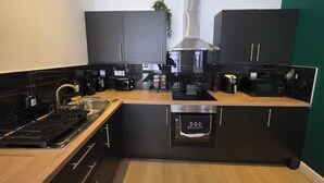 A modern kitchen with black cabinets, stainless steel appliances, and a wooden countertop.