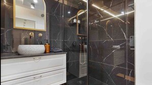 A modern bathroom with a marble vanity, a large mirror, and a glass-enclosed shower area. - La Perle - T2 with terrace, air conditioning & parking near Toulouse city center (Toulouse)