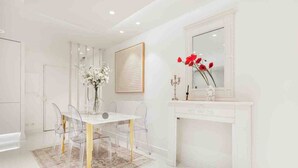 A modern, white-themed room with a dining table, chairs, a vase with flowers, a mirror, and a fireplace. - La Perle - T2 with terrace, air conditioning & parking near Toulouse city center (Toulouse)