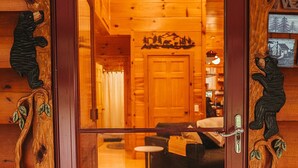 L’intérieur d’une cabane en bois, avec une porte centrale, un canapé et une petite table.