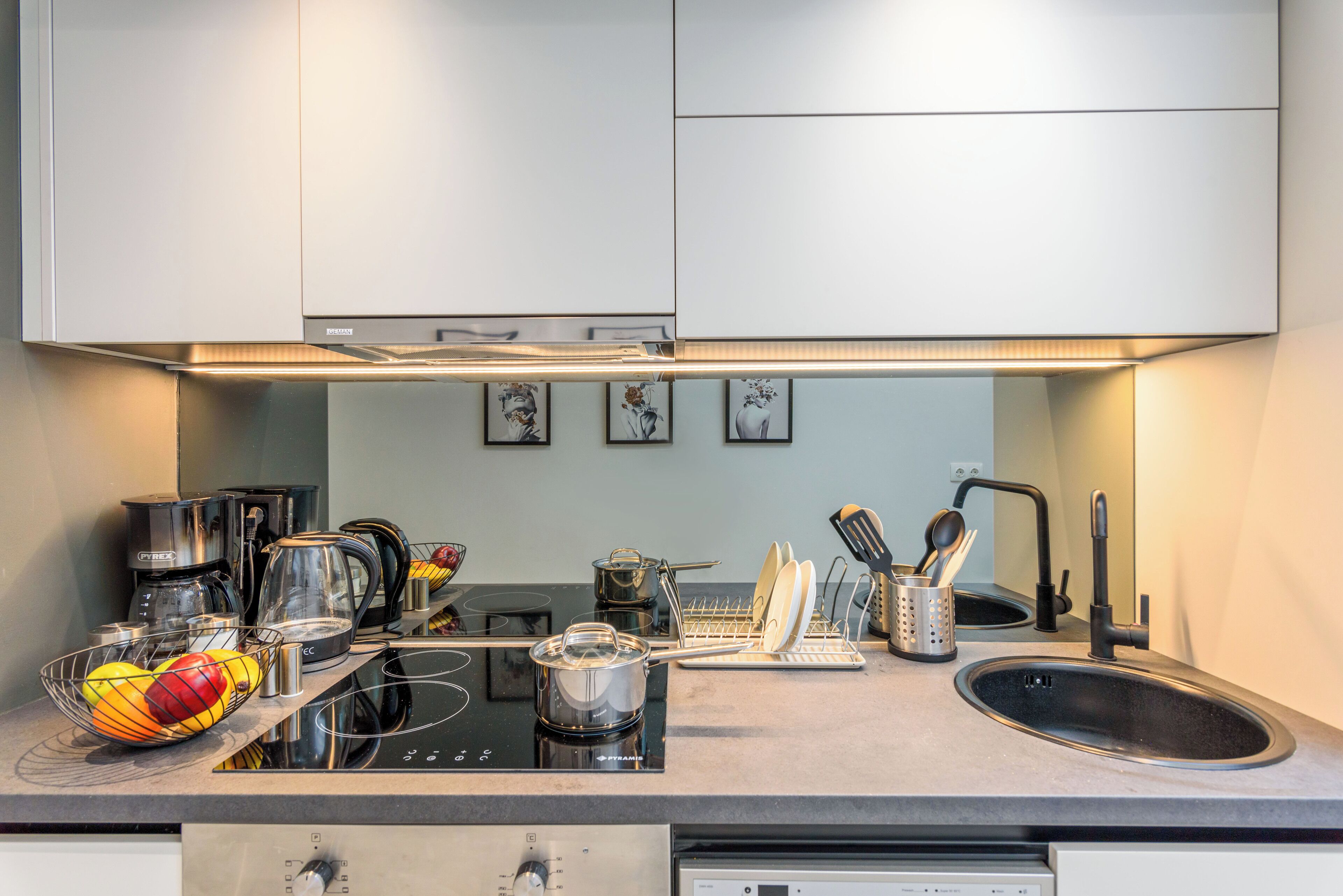 A modern kitchen with stainless steel appliances, a black sink, and a dish rack.