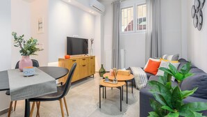 A modern living room with a sofa, a TV, a dining table, and a coffee table. - Penelope's Charming 2-BR Apt in Athens (Athens)