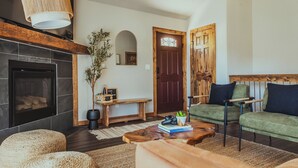 A cozy living room with a fireplace, green sofa, wooden coffee table, and a bench.