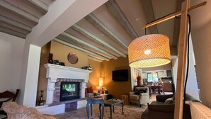 A cozy living room with a fireplace, comfortable seating, and a large hanging light fixture.