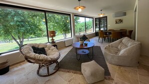 A spacious living area with large windows, a dining table, and comfortable seating.