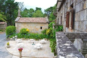 Un patio con edificios de piedra, mobiliario exterior y vegetación.