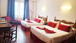 Habitación de hotel con dos camas, un escritorio y una silla.
