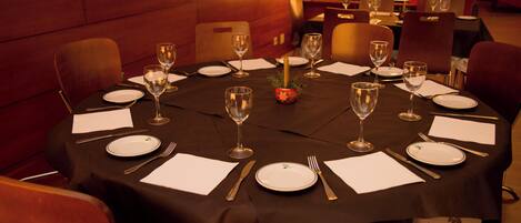 A round dining table set for a meal with chairs around it.
