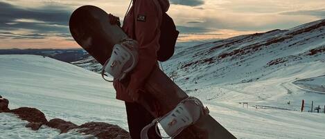 A person standing on a snowy slope with a snowboard, wearing a jacket and a backpack.