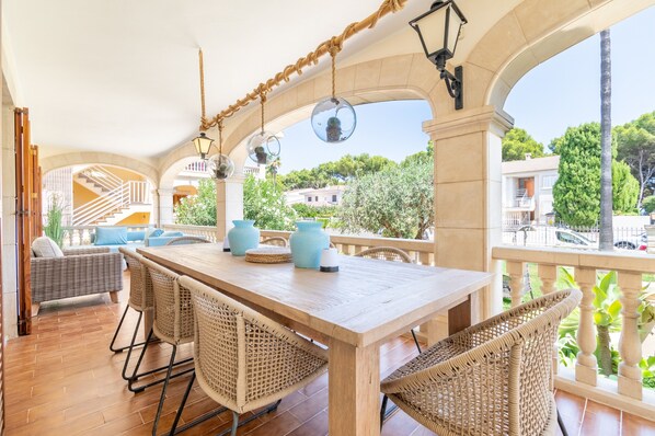 An outdoor patio with a wooden table, wicker chairs, and hanging spherical decorations.