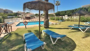 A poolside area with lounge chairs, a thatched umbrella, and a lifebuoy.