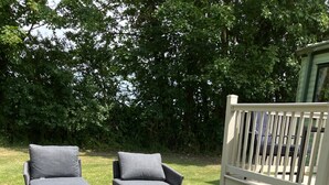 Two grey lounge chairs with cushions on a grassy lawn, a white fence, and dense green foliage in the background. - Peace & Tranquility at The Hideaway Stay (Alford)