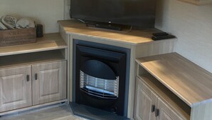 A compact kitchen with wooden cabinets, a built-in TV, and a fireplace. - Peace & Tranquility at The Hideaway Stay (Alford)