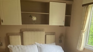 A bed with white bedding and a patterned throw blanket. There are two white headboards and a small shelf with a vase of flowers. - Peace & Tranquility at The Hideaway Stay (Alford)