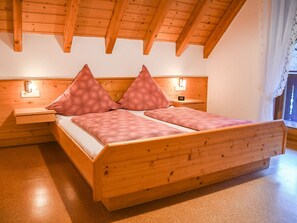 Un lit en bois avec deux tables de chevet, une tête de lit dotée d’un éclairage intégré et une fenêtre avec des rideaux.