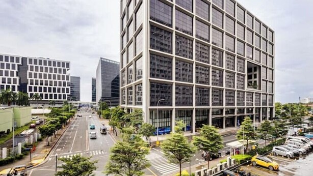 A modern building with a grid-like facade, surrounded by a street with cars and trees. - The Golden Shore Suites (Pasay)