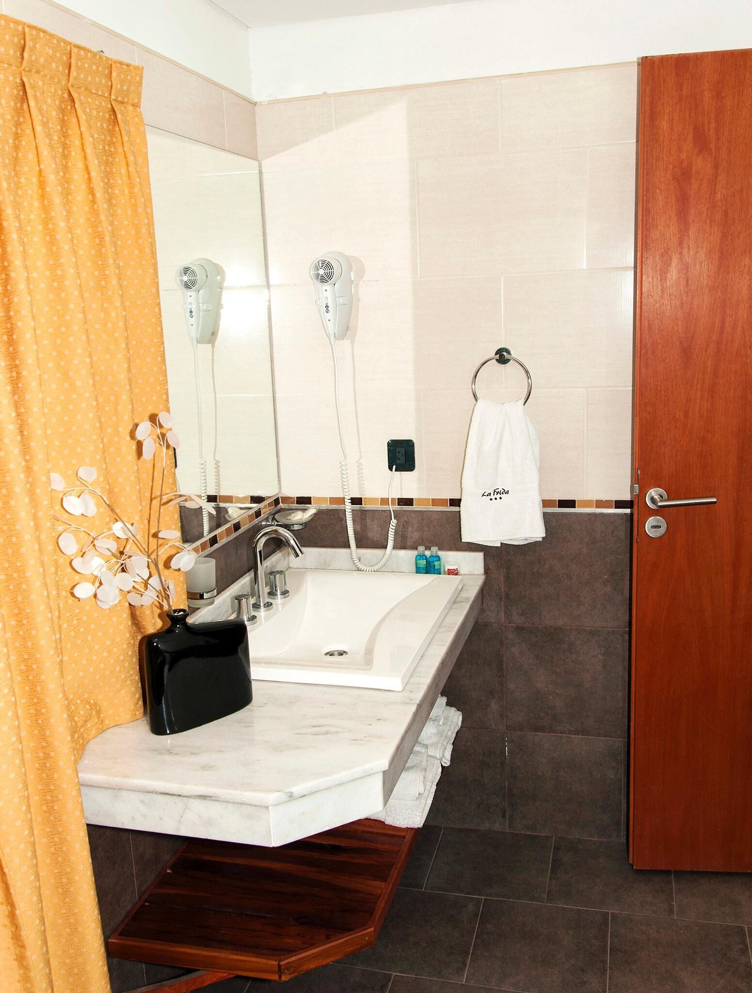Un baño con lavamanos doble, espejo, perchero y puerta.