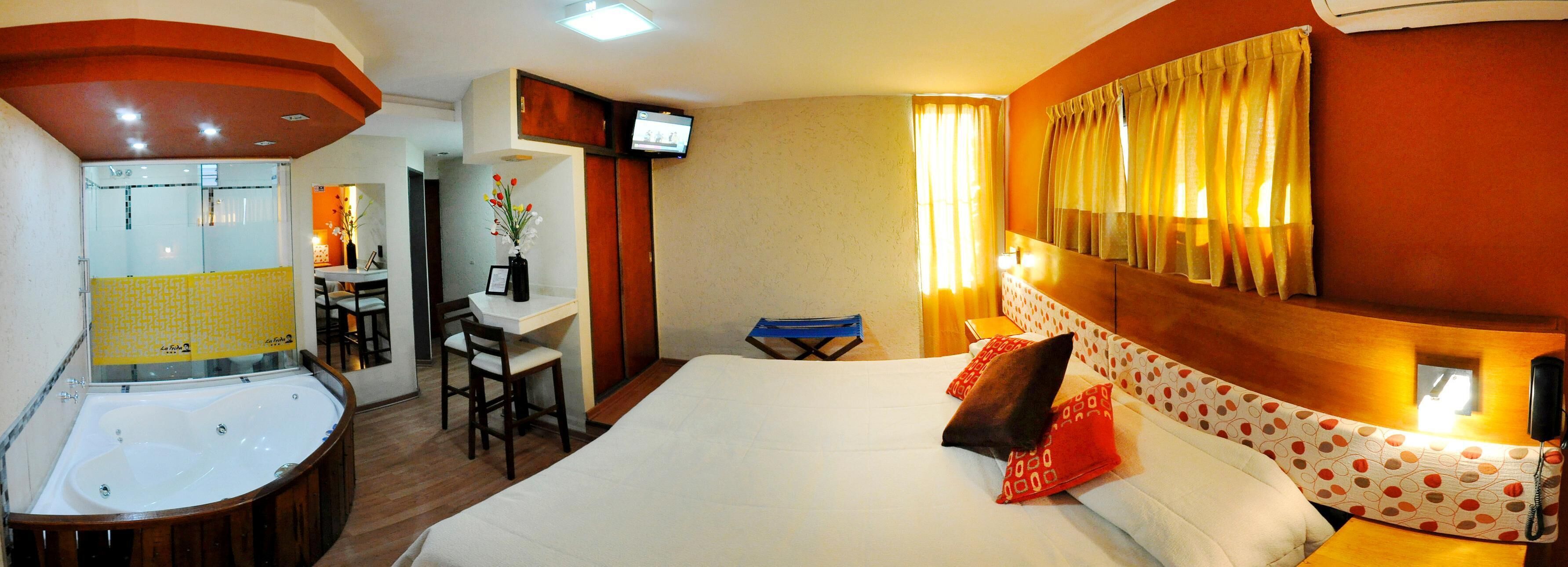 A hotel room with a bed, a desk, a TV, and a bathroom.