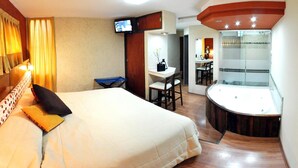 Ein Hotelzimmer mit Bett, Schreibtisch, Stuhl, Fernseher und einem Badezimmer mit Duschkabine.