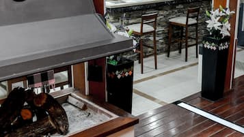 Zona de bar con una parrilla grande, suelo de madera y una barra con el nombre 'La Frida'.